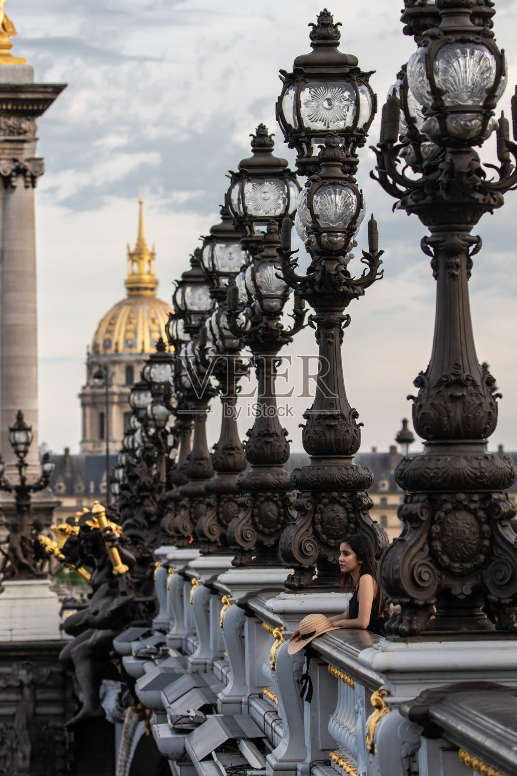 在巴黎亚历山大三世桥栏杆上休息的苗条年轻女子照片摄影图片