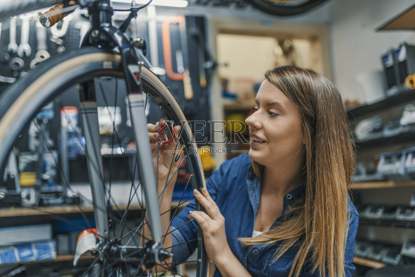 时髦的自行车机修工女人在车间做他的专业工作照片摄影图片