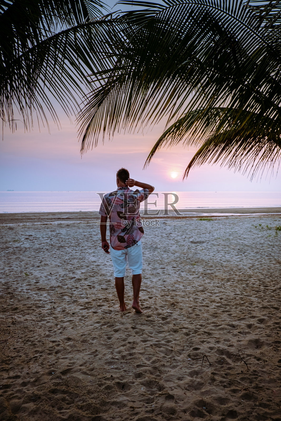 泰国春蓬,男人们在海滩看日落照片摄影图片