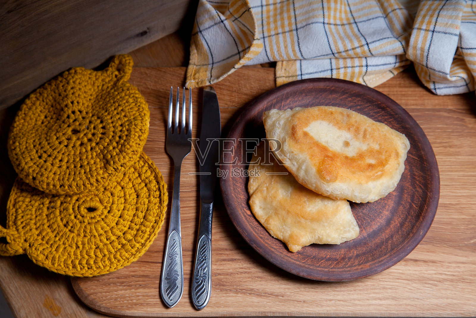 木桌上一盘配着刀叉的油炸肉馅饼照片摄影图片