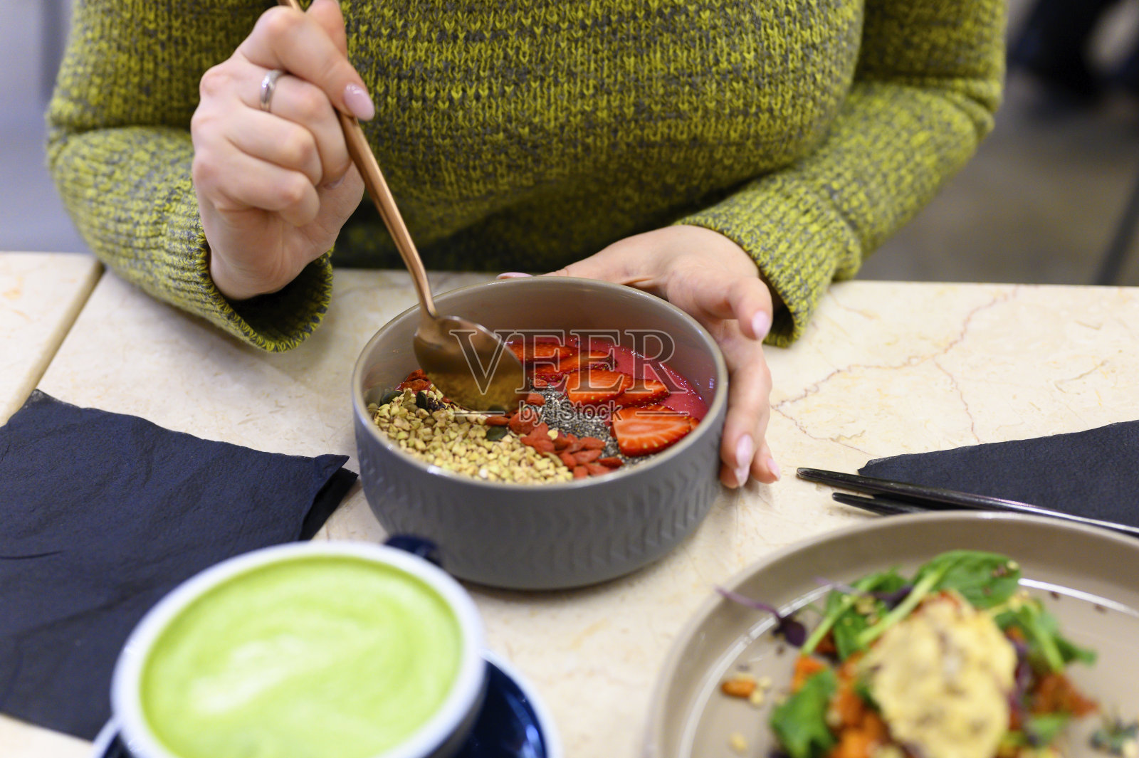 生健康食品和女人早餐,准备吃。桌上放着冰沙碗、鹰嘴豆泥吐司和抹茶拿铁绿茶杯照片摄影图片