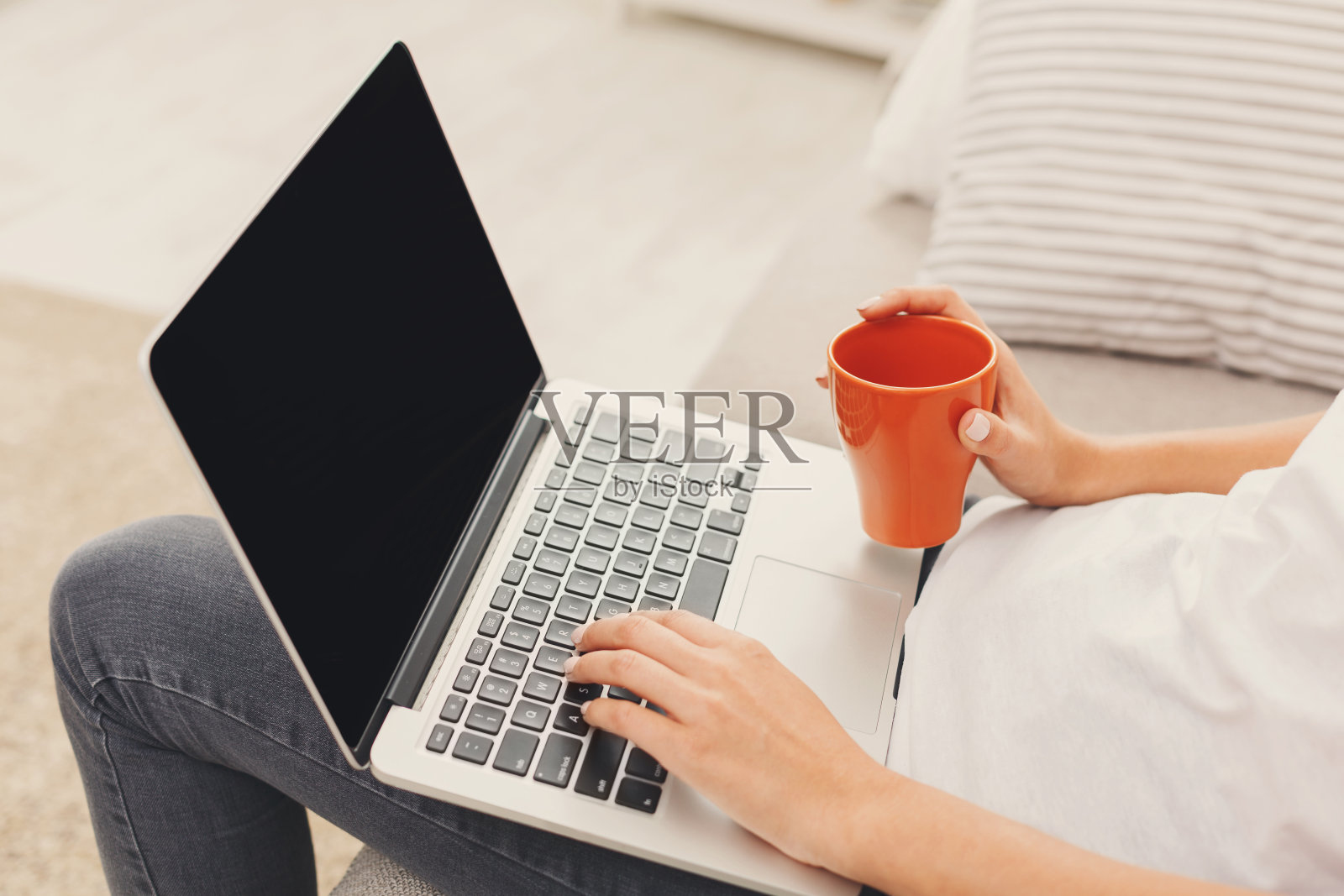 一个面目全非的女孩拿着笔记本电脑坐在沙发上照片摄影图片