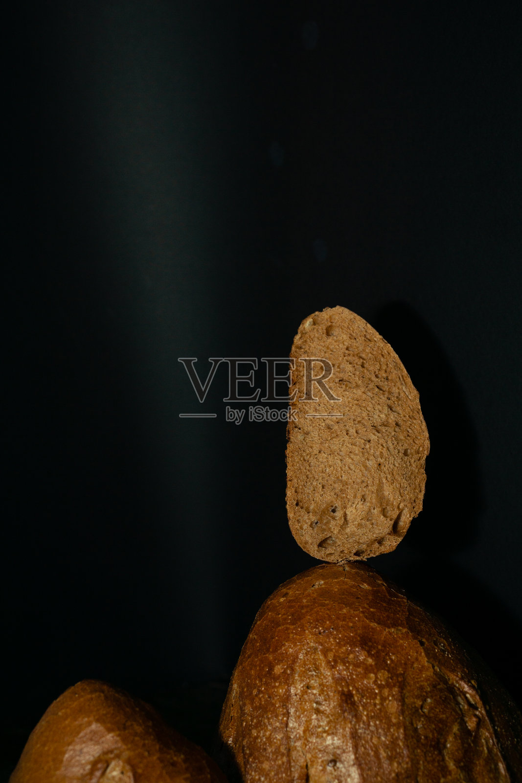 在黑色背景上的新鲜黑色面包条的边缘。酵母产品照片摄影图片