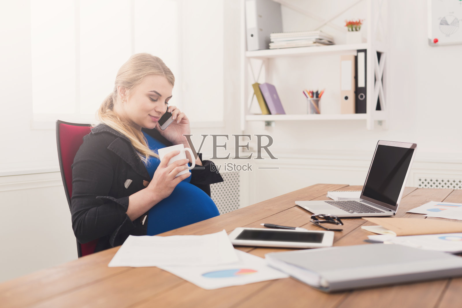 怀孕的女商人在办公室打电话照片摄影图片
