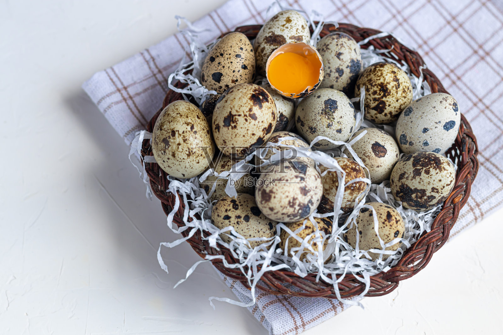 鹌鹑蛋被放在柳条篮子里,旁边是一根柳条。为复活节做准备。在白色背景上。照片摄影图片
