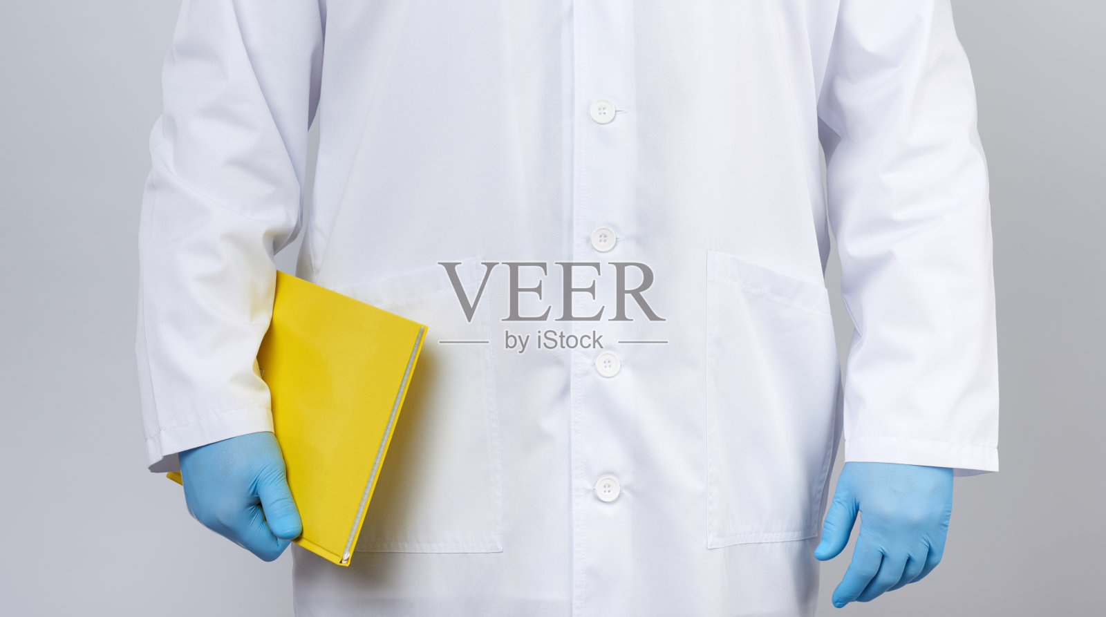 穿白大褂手持黄色笔记本的男医生照片摄影图片