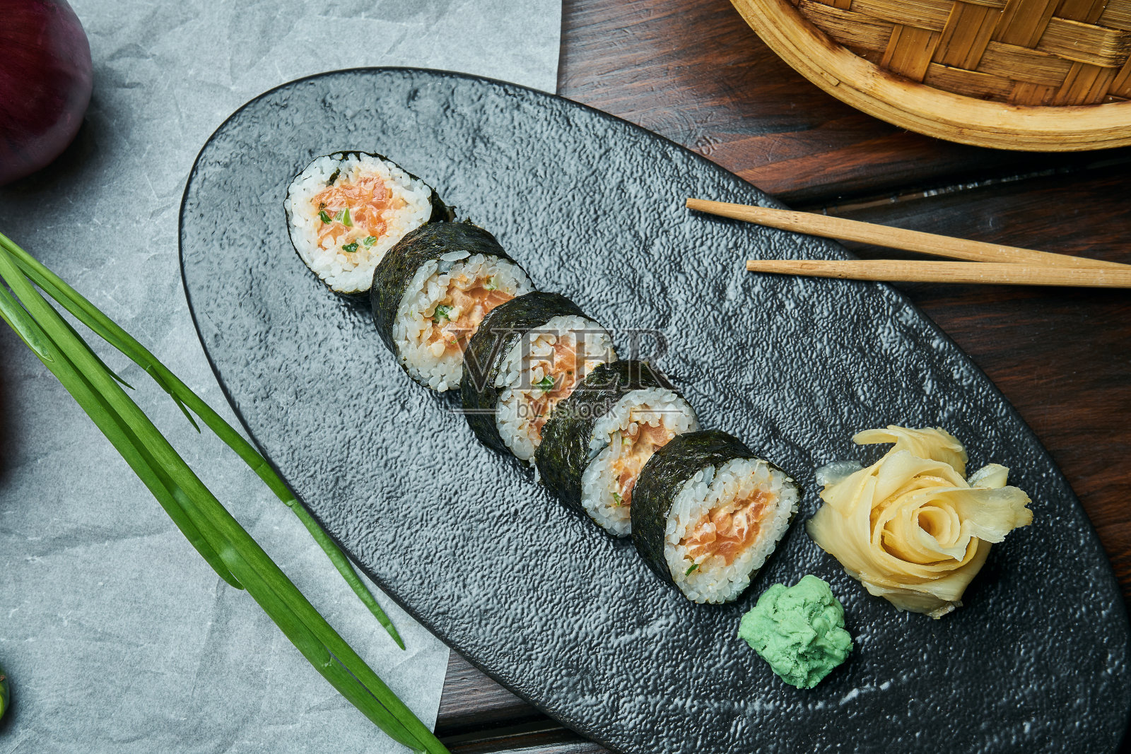 经典的日本三文鱼寿司卷。用筷子夹在黑色的盘子上。日本料理。健康的海鲜照片摄影图片