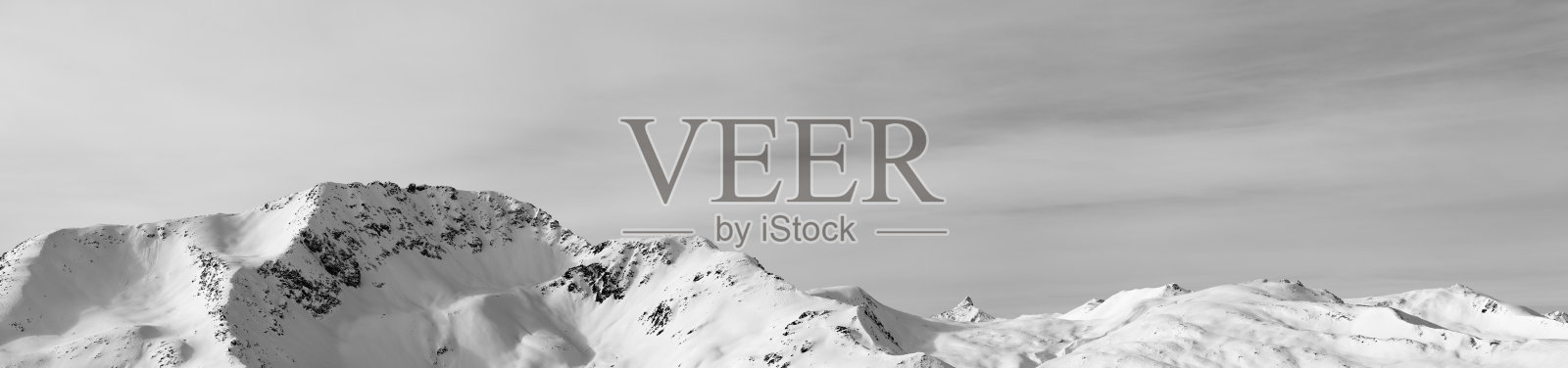 全景的高山与雪坡和阳光下多云的天空照片摄影图片