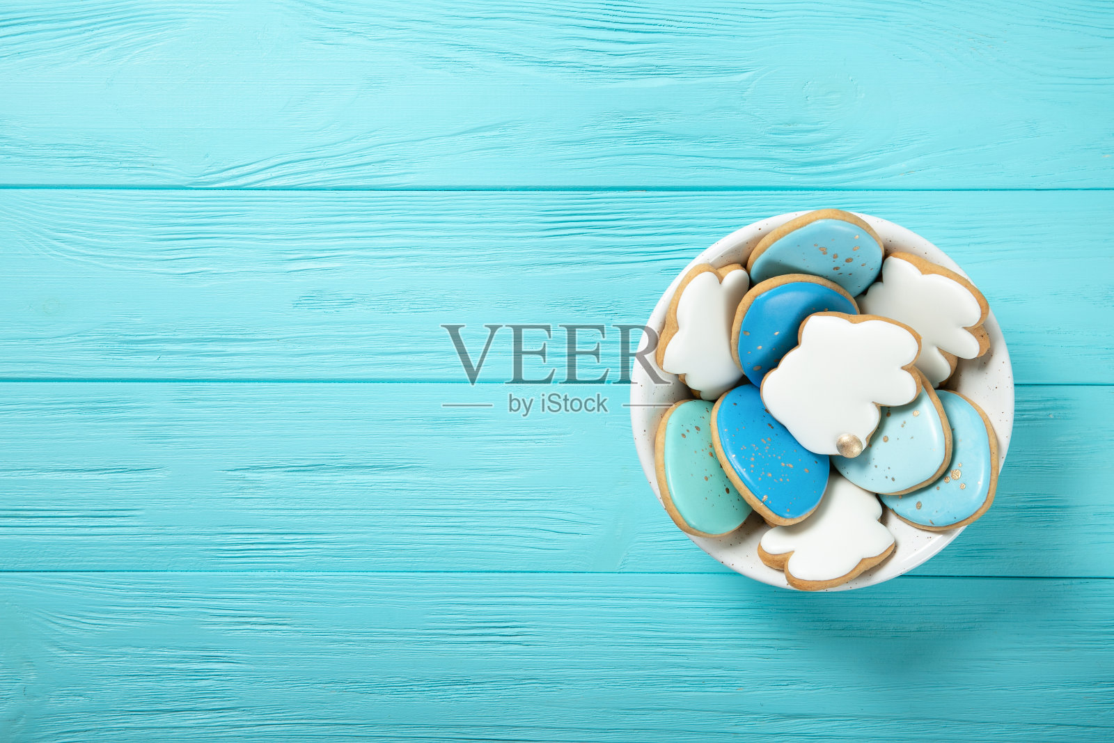 蓝色背景的盘子里装着复活节饼干。复活节彩蛋。复活节兔子。文本。从上面的观点照片摄影图片