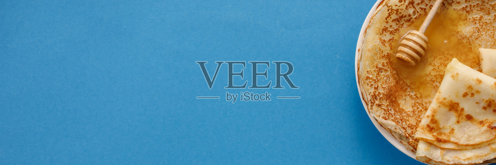 美味的自制煎饼,蓝色背景上有蜂蜜。顶视图,特写。传统节日庆祝概念。俄文翻译宽和快乐的Shrovetide Maslenitsa。照片摄影图片