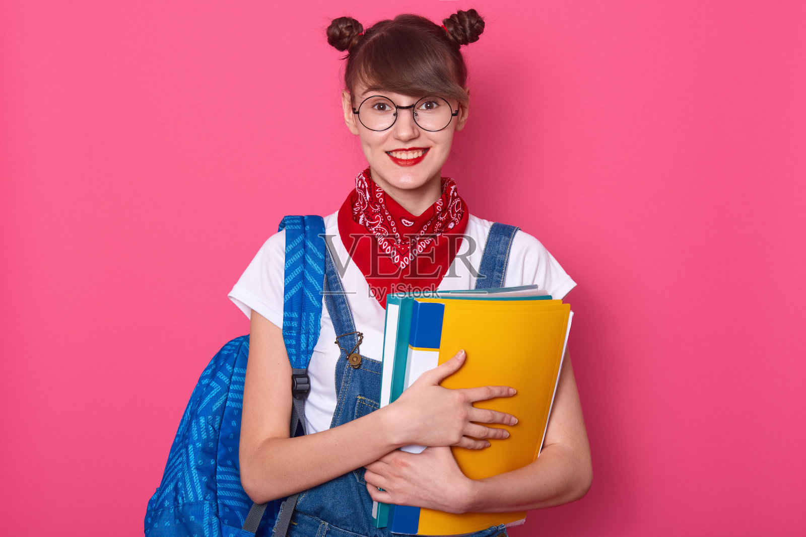 扎着两个发髻,手拿蓝黄色文件夹,穿着休闲的快乐妇女的横向照片照片摄影图片