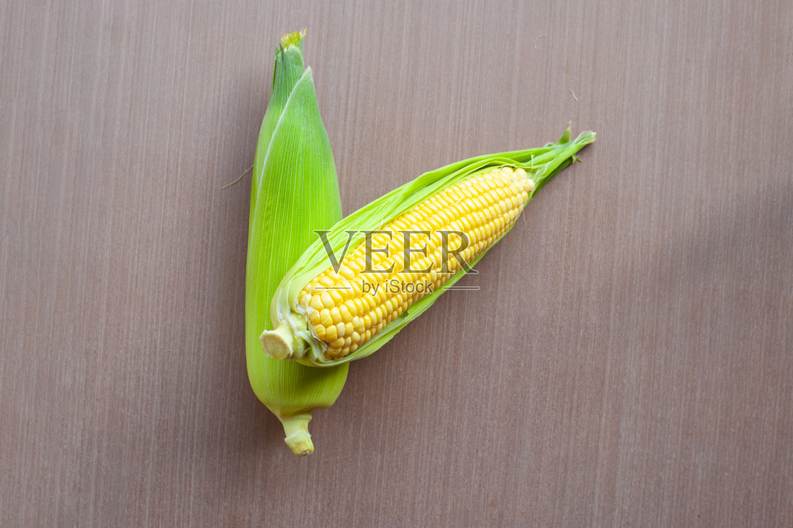 木地板上放着新鲜的黄色玉米。特写镜头,照片摄影图片