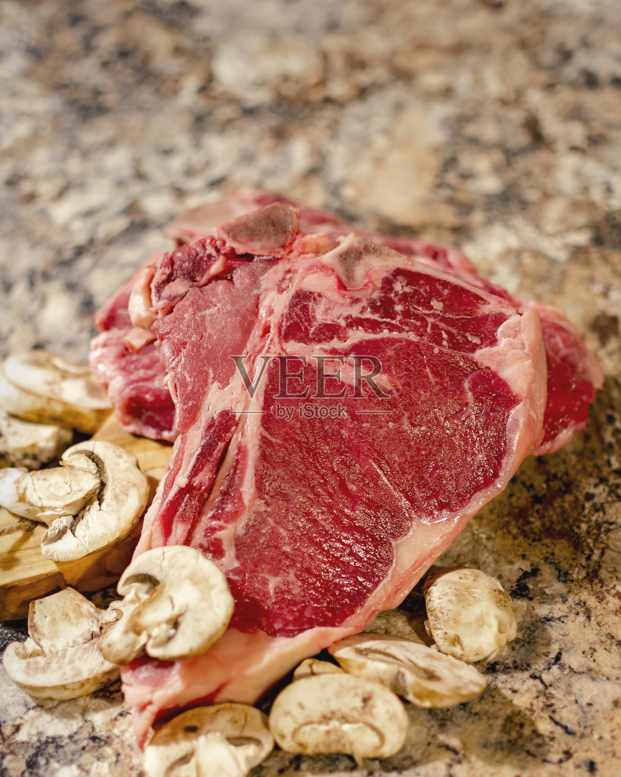 T形骨或上等腰牛排,放在切菜板上,配蘑菇。照片摄影图片