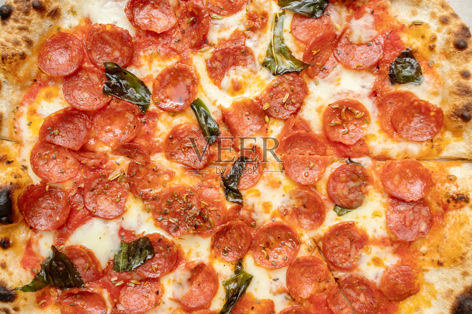 有害的高脂肪饮食。披萨配意大利辣香肠、奶酪、罗勒和香料照片摄影图片