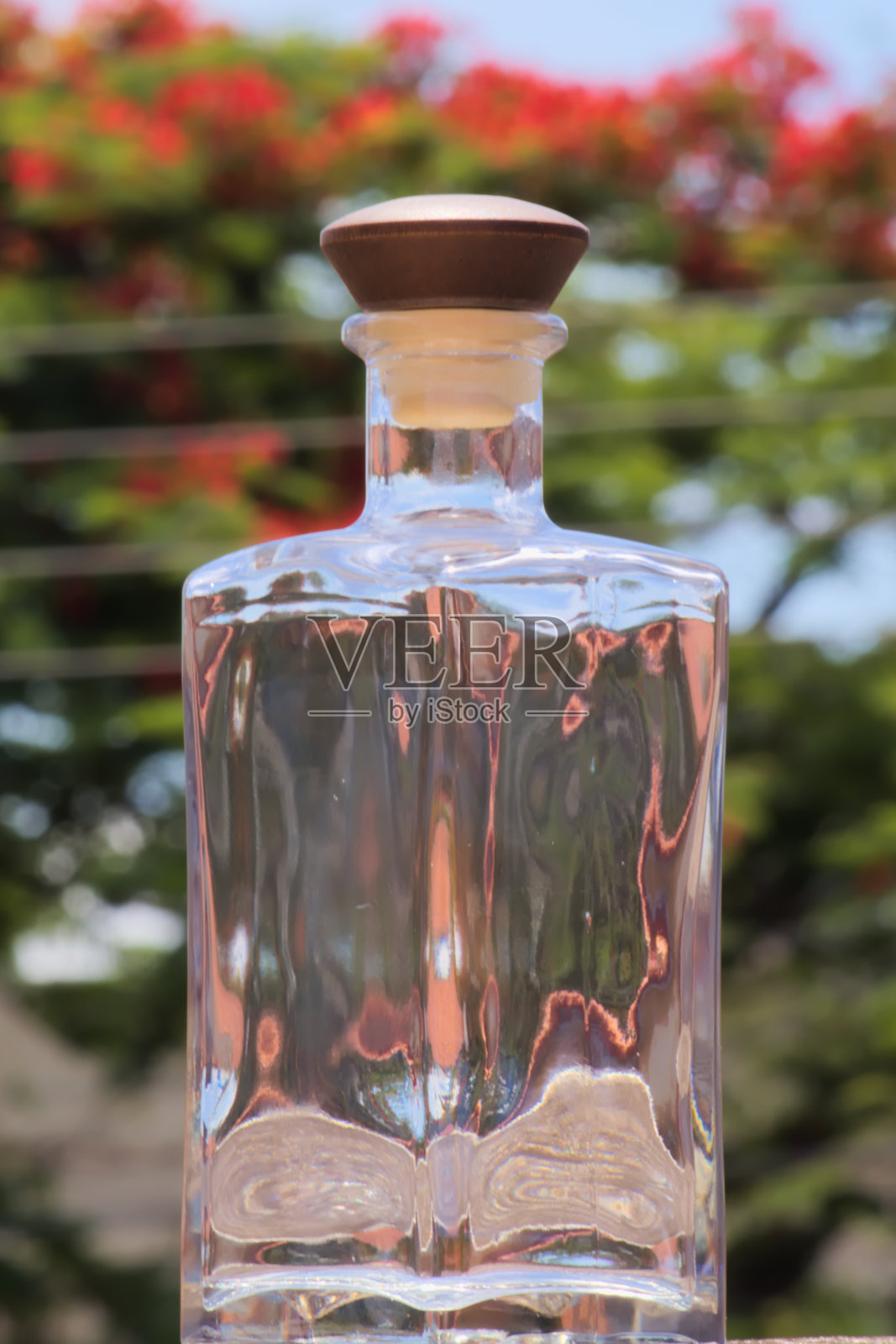 一个半透明的玻璃瓶与模糊的树木在背景的特写。照片摄影图片