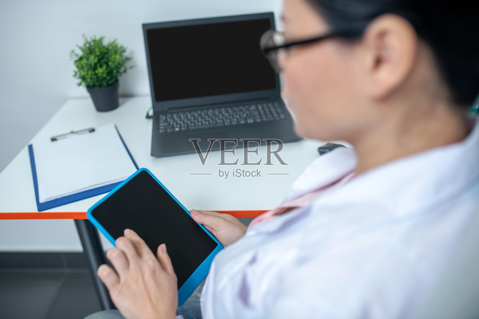 戴着眼镜拿着药片的黑发女医生照片摄影图片