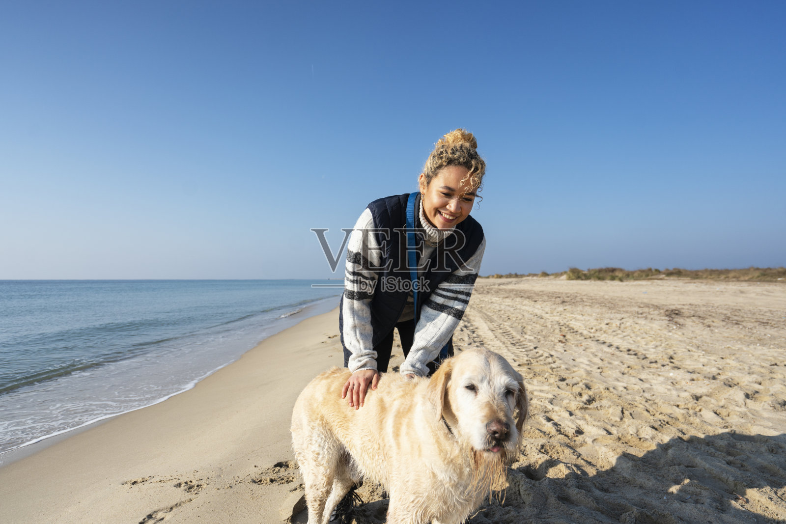 一个年轻女人和她的狗在海滩上照片摄影图片