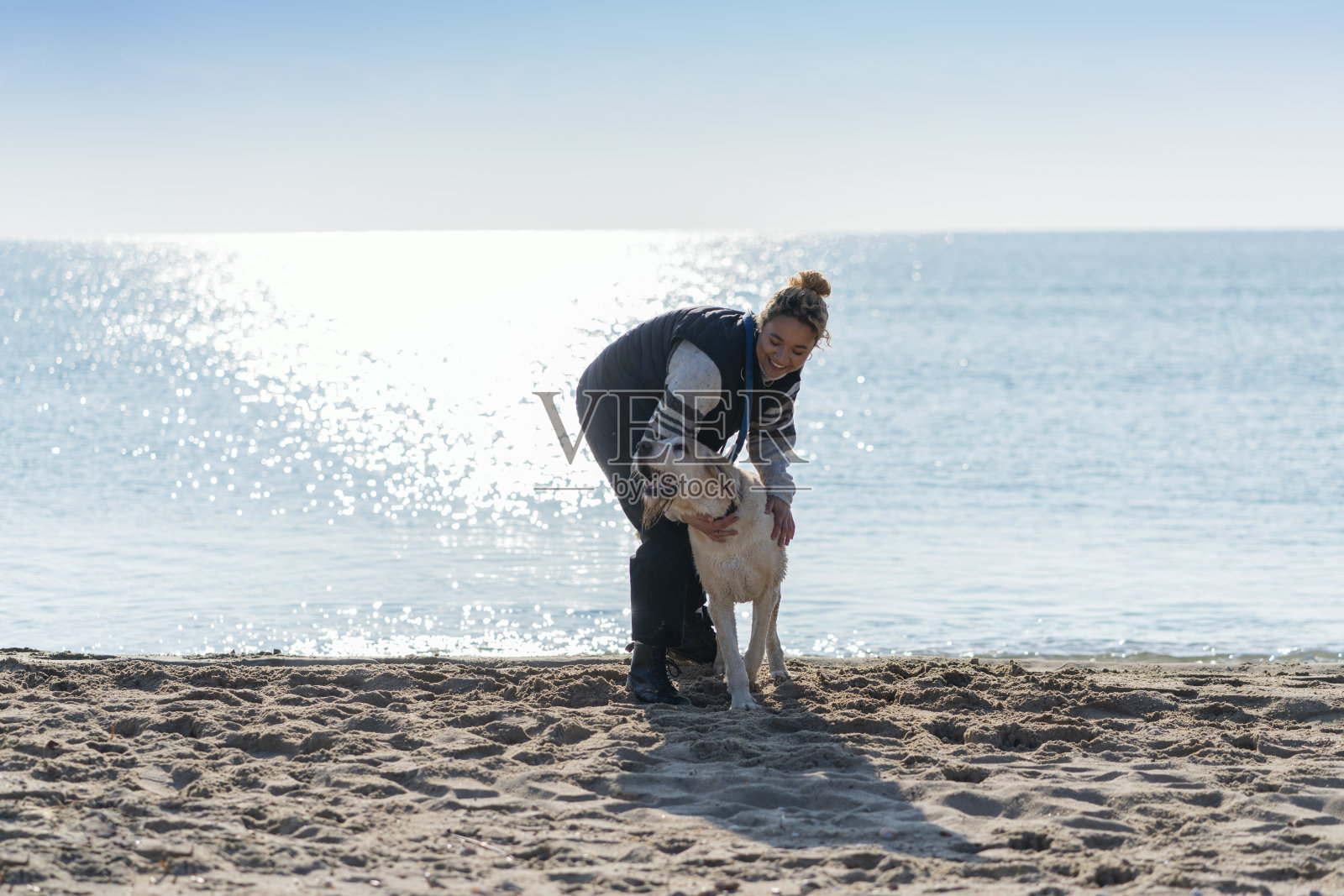 一个年轻女人和她的狗在海滩上照片摄影图片
