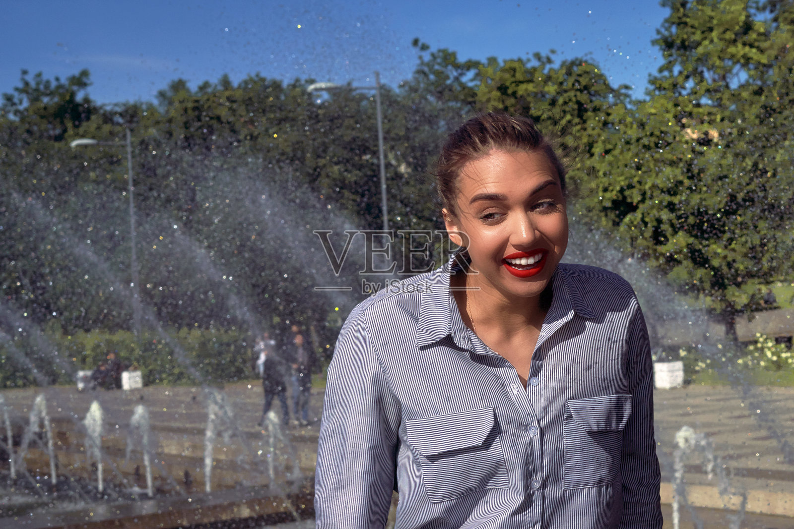 阳光明媚的夏日,女孩在喷泉旁,湿发,笑容灿烂照片摄影图片