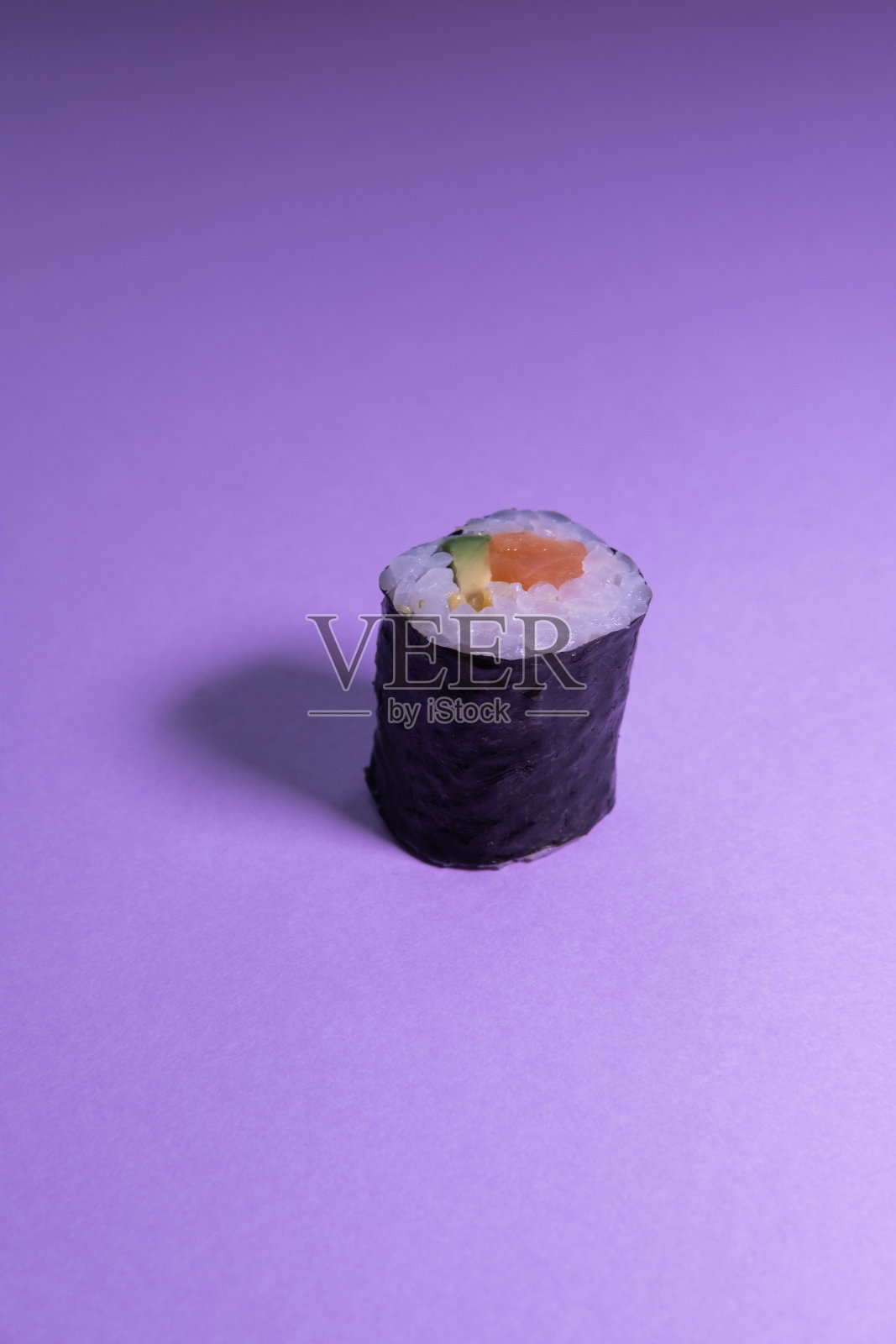 紫色背景上孤立的鳄梨和三文鱼寿司。垂直的概念图。日本的食物。照片摄影图片