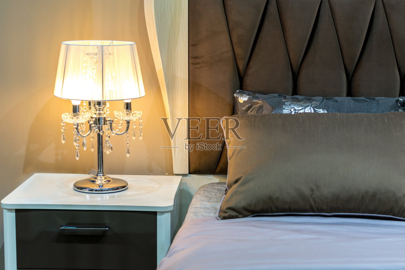 明亮的卧室,白色的床头柜。优雅的吊灯。照片摄影图片