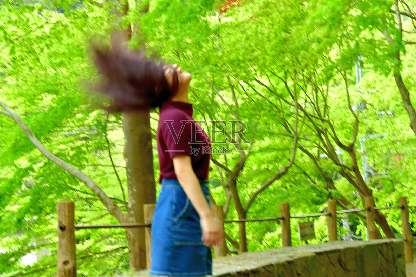 年轻的日本女人在新鲜的枫树叶下旋转她的长发照片摄影图片