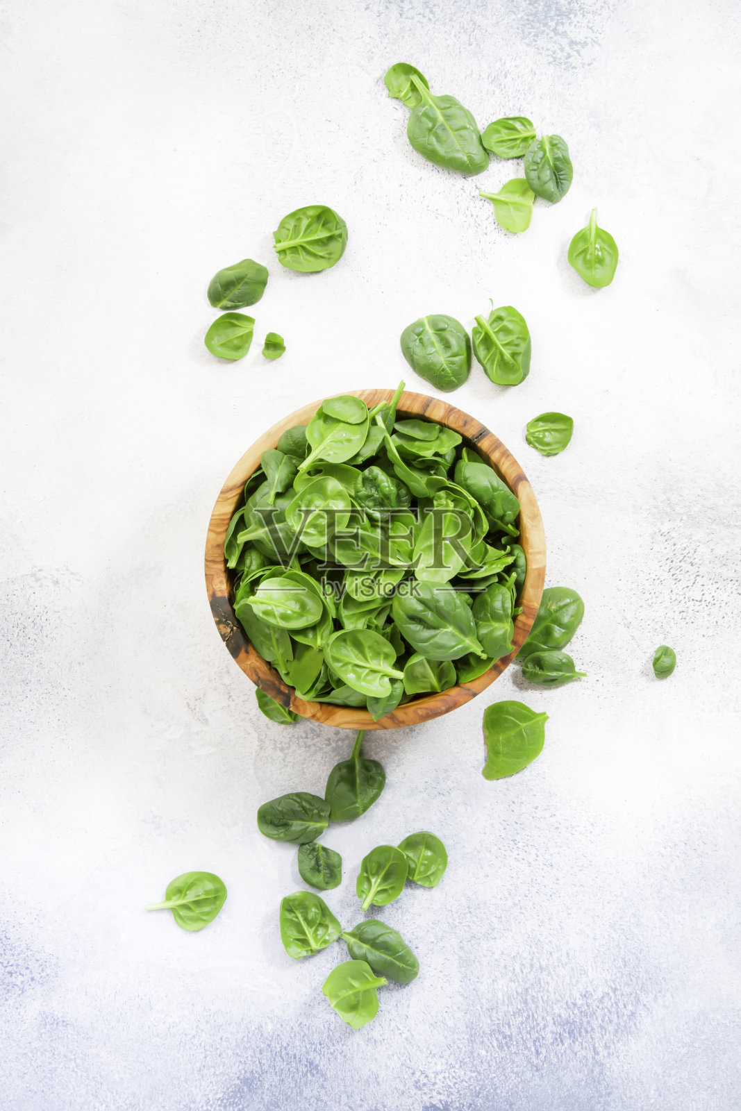 灰色石桌木碗中的新鲜小菠菜叶照片摄影图片