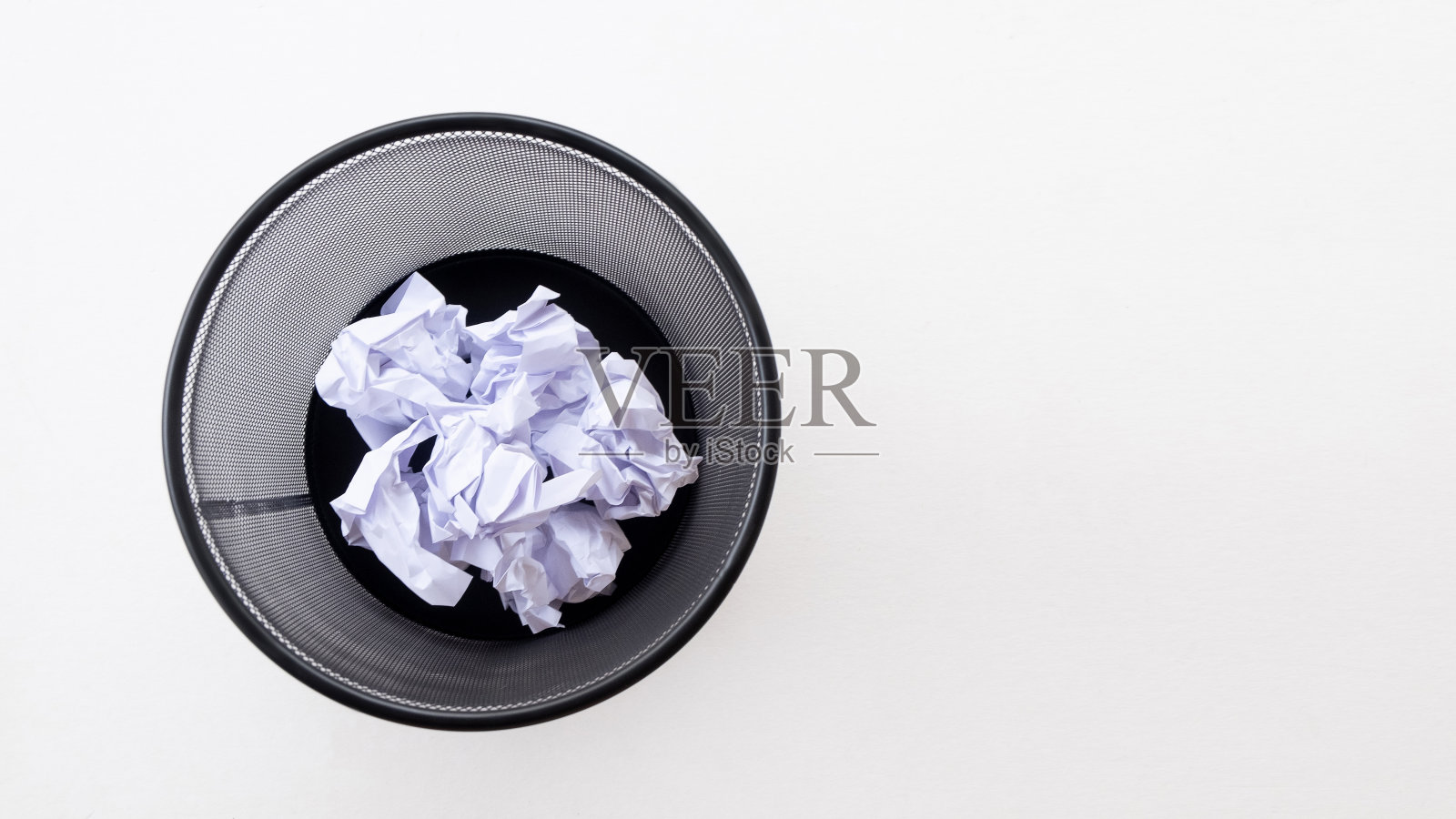 垃圾桶里的皱巴巴的纸,背景是白色。照片摄影图片