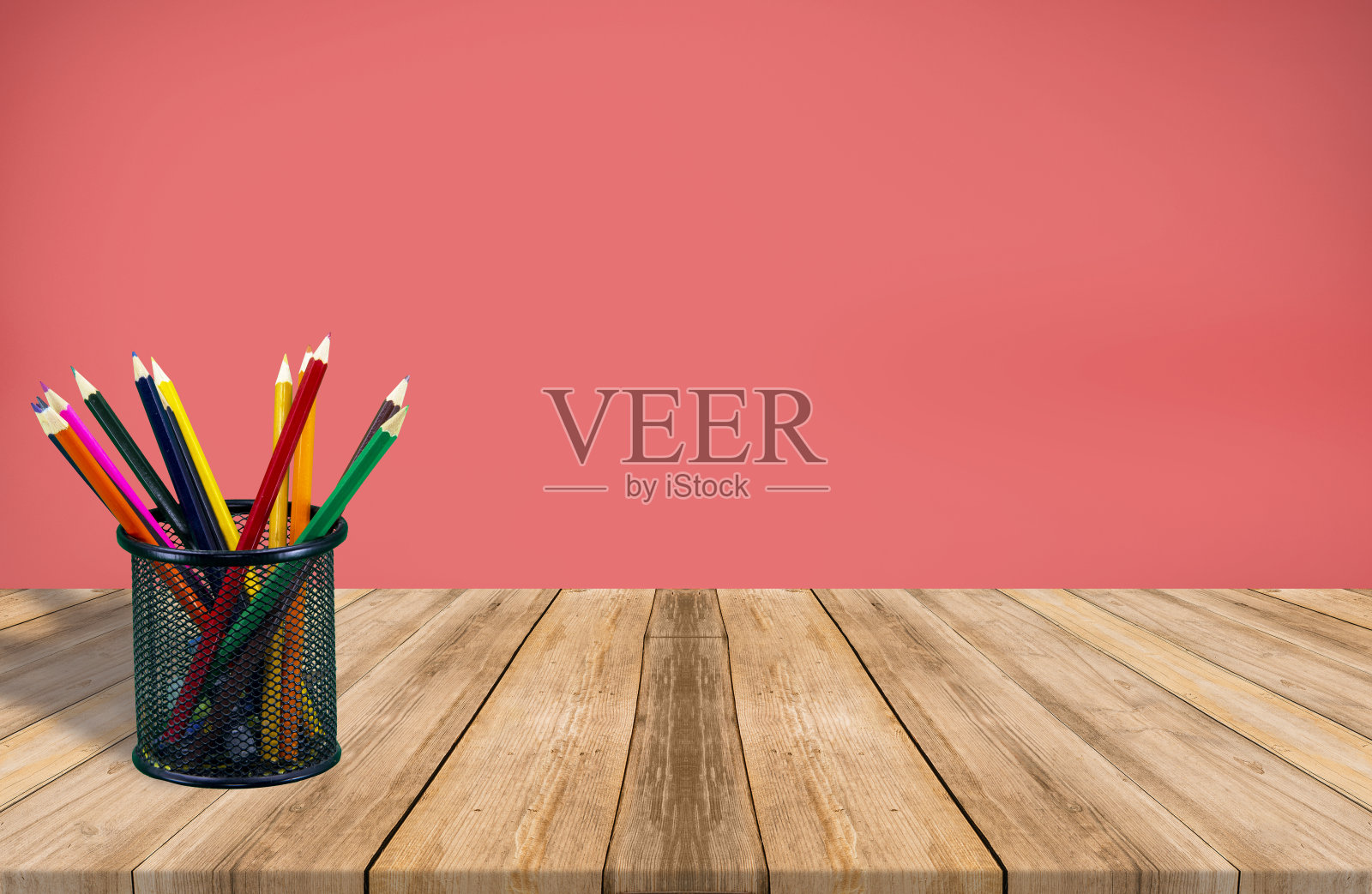 空房间内装满彩色铅笔的笔筒,木地板红色背景照片摄影图片