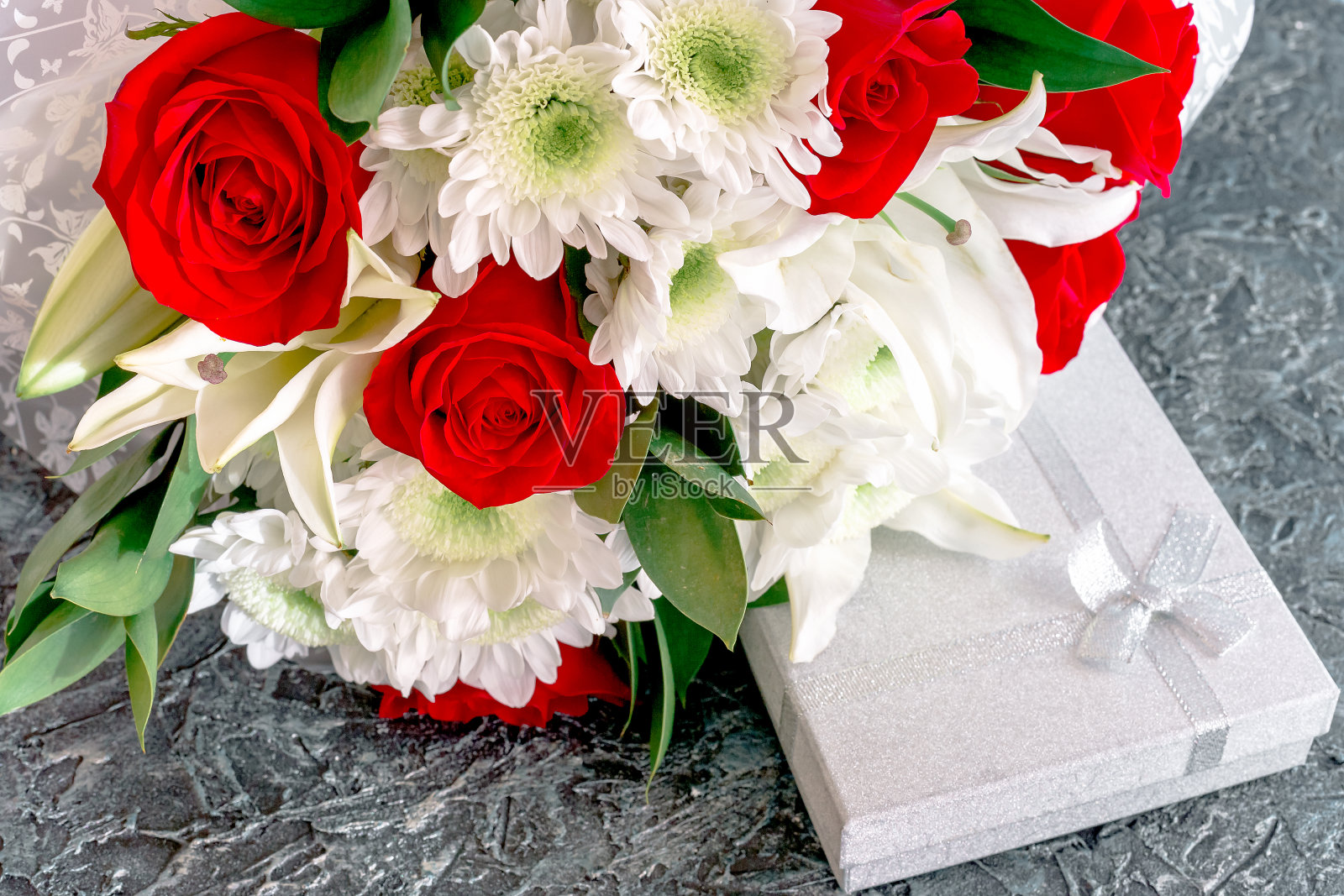 背景,为祝贺女性而设计的。一束玫瑰、百合和菊花,银盒子里装着礼物。照片摄影图片