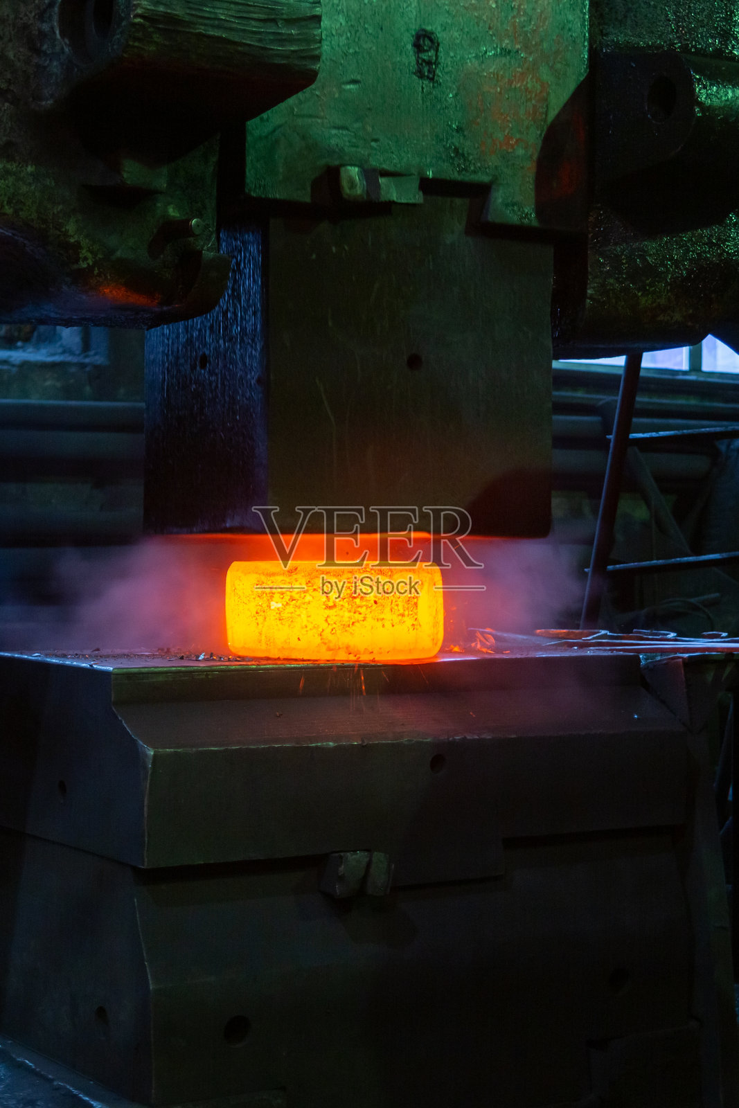 热钢手工锻造过程的特写图片与大型机械锤机照片摄影图片