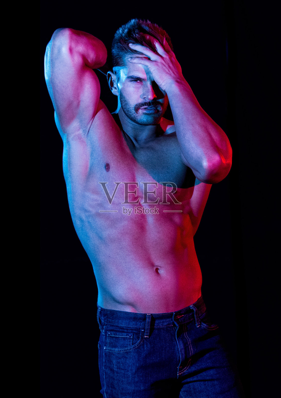 白人男子站在黑色背景前,穿着裤子照片摄影图片