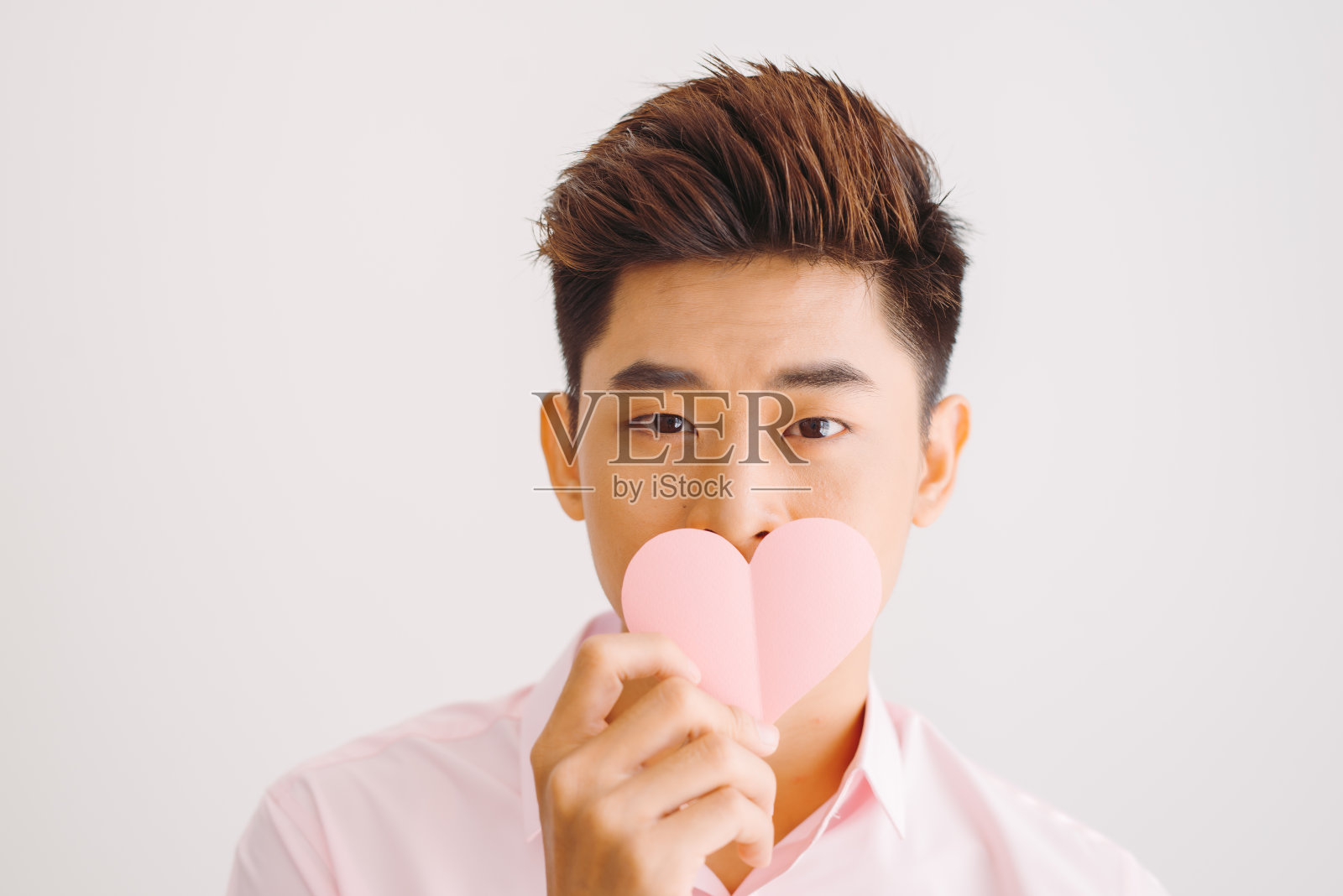 年轻英俊的亚洲男子在白色背景下阅读心形贺卡照片摄影图片
