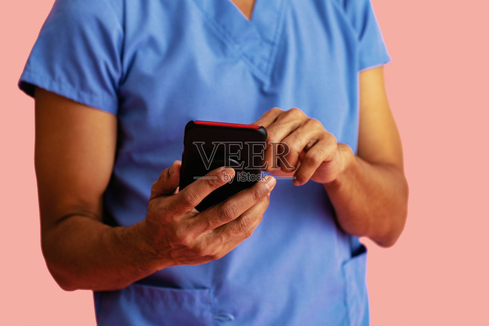 穿蓝色工作服的男医生或护士手持手机书写细节照片摄影图片