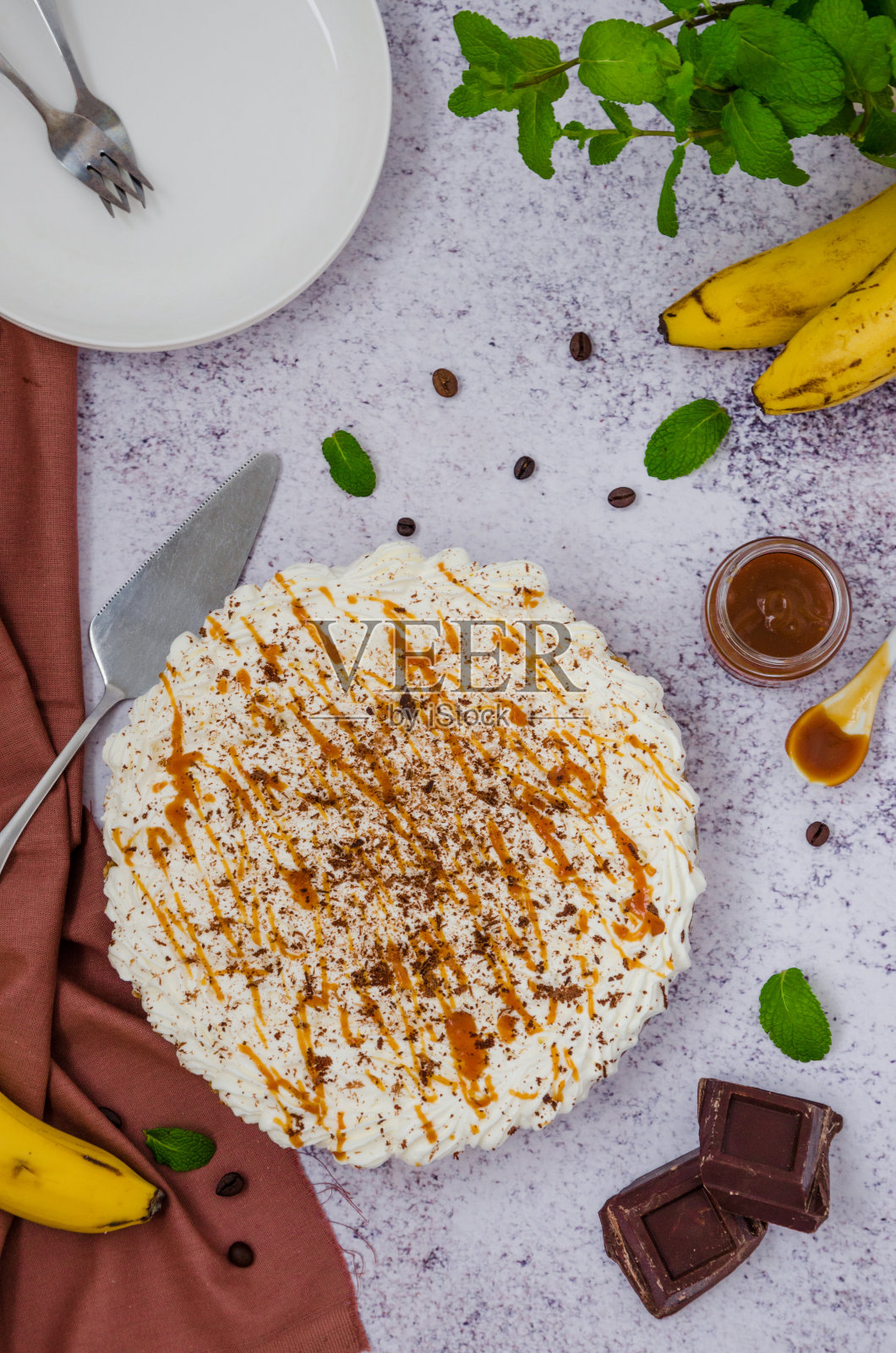 传统的香蕉派配新鲜香蕉,奶油,巧克力,咖啡和太妃糖。没有烘焙甜点。垂直方向。前视图。照片摄影图片