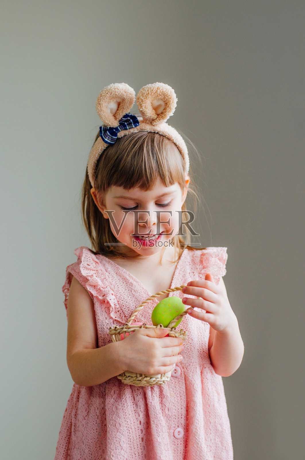 小女孩抱着兔子耳朵,拿着复活节彩蛋照片摄影图片