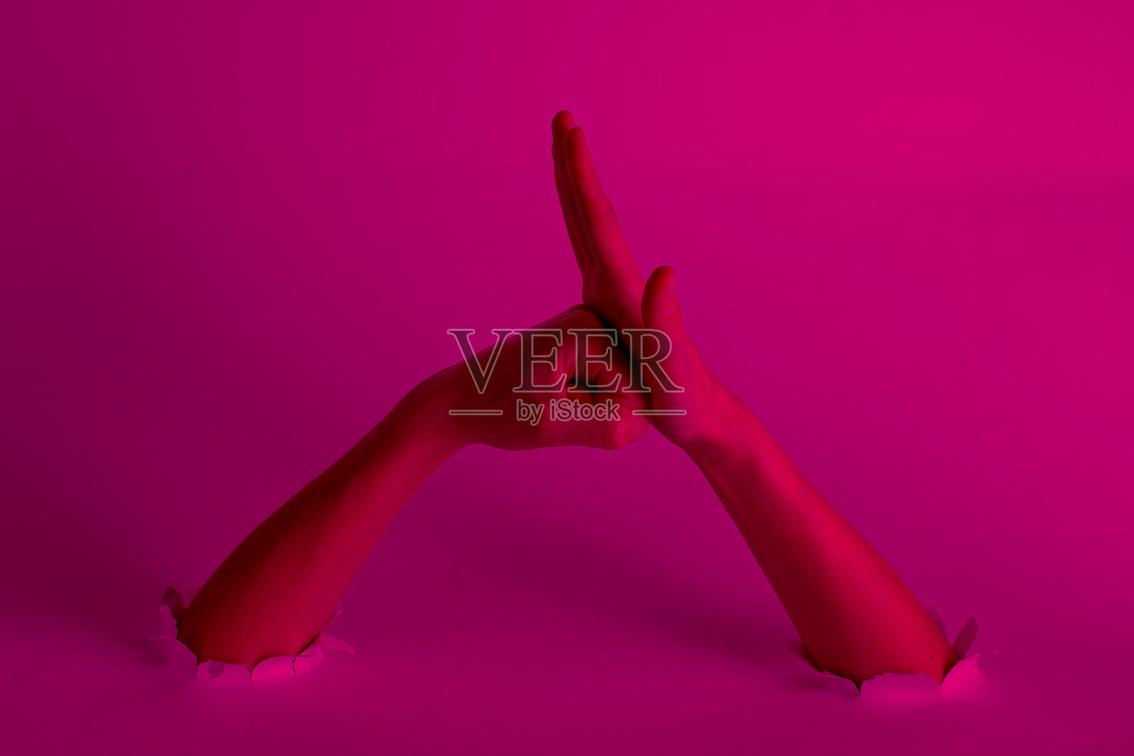 女性拳头穿过粉色霓虹灯的破洞,创意艺术照片摄影图片