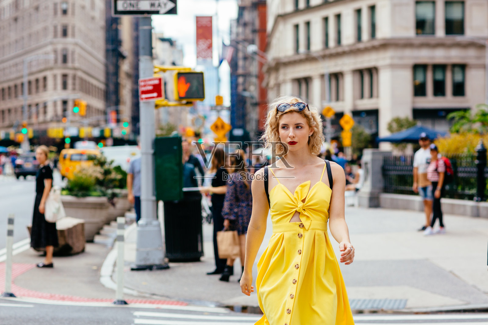 一个穿着黄色衣服的女人在纽约的大街上叫出租车照片摄影图片