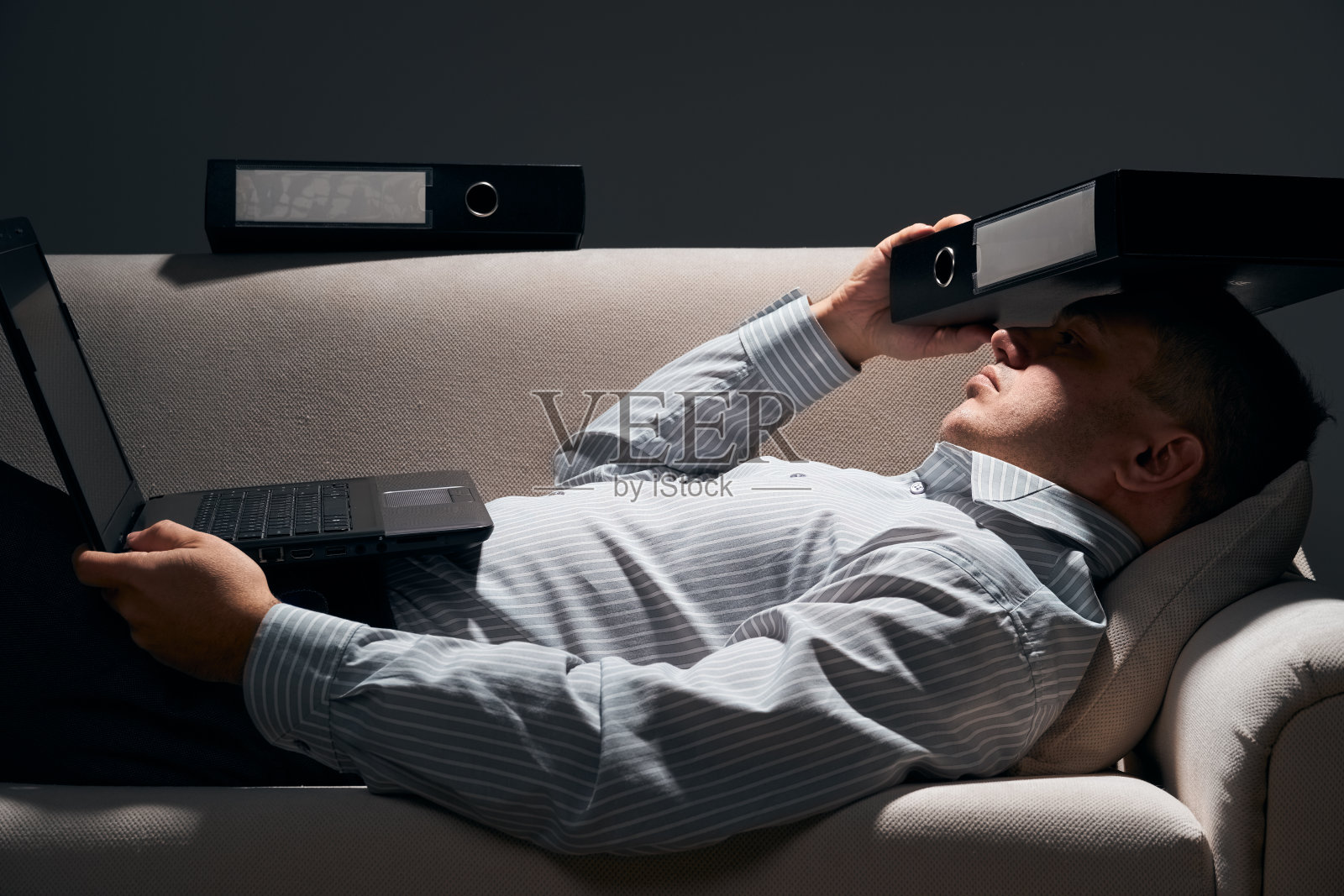 商人躺在沙发上用笔记本电脑休息照片摄影图片