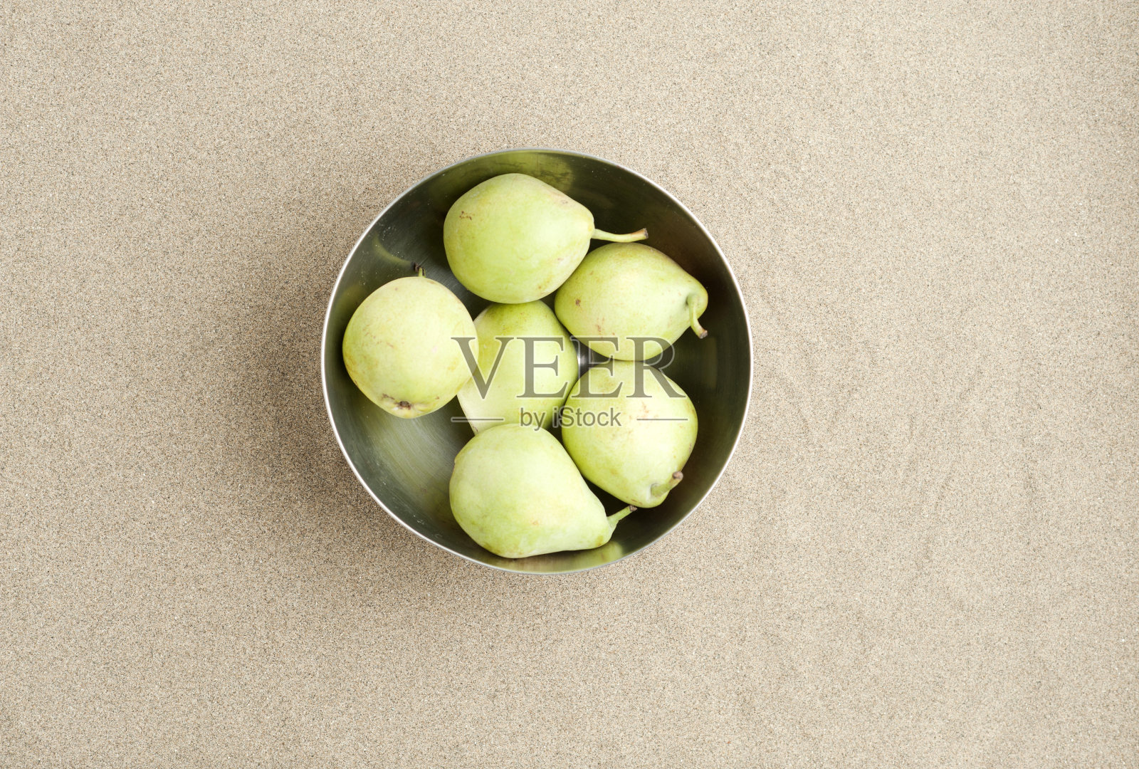 一套绿色的梨在金属碗,在沙滩上,空间写作,俯视图照片摄影图片