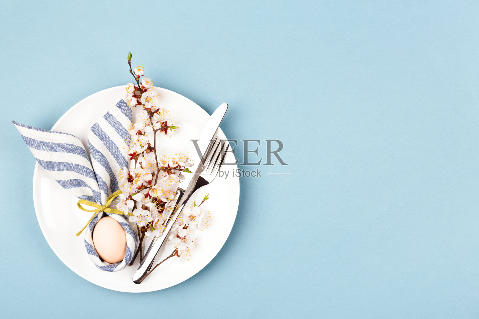 复活节餐桌上用餐巾裹着蛋的复活节兔子。照片摄影图片