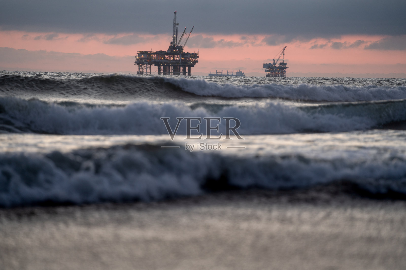 海上石油和天然气压裂和钻井平台与太平洋的前面和美丽的日落背后与戏剧性的云照片摄影图片