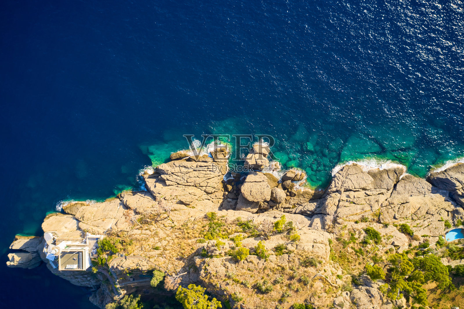 灯塔俯视图站在岩石山附近的大海与蓝色的水在波托菲诺,意大利。利古里亚的大海用巨石冲刷着海岸。照片摄影图片