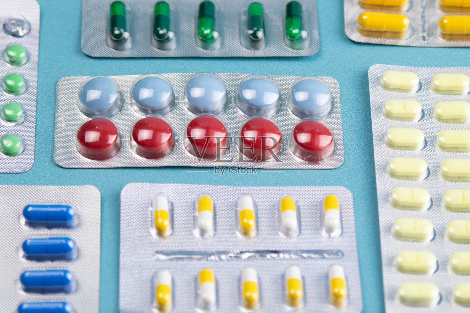 不同颜色的药丸放在蓝色的背景上。彩色抗菌丸、胶囊类药物照片摄影图片