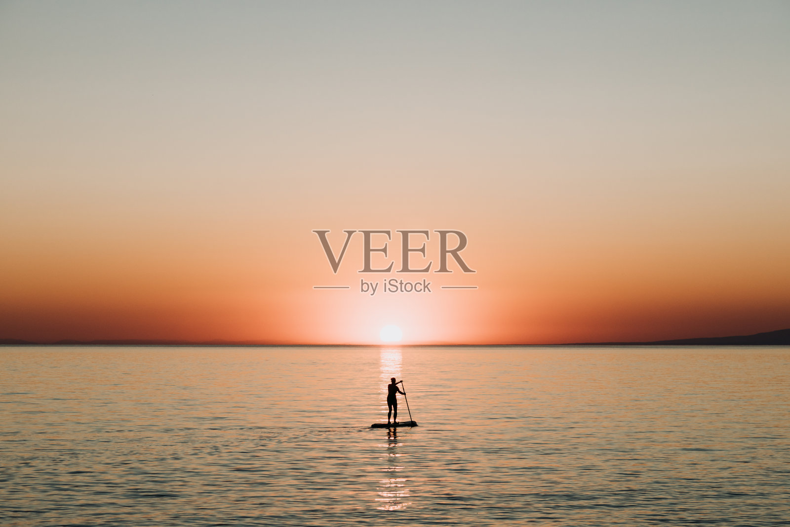 日落时分,一个女人在海上划船照片摄影图片