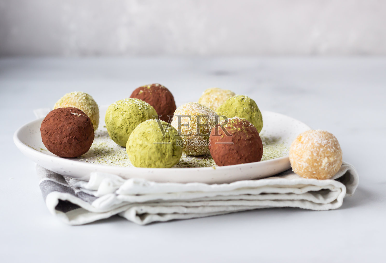 生能量球配抹茶粉、可可粉和椰子片,底色浅灰色。有选择性的重点。照片摄影图片