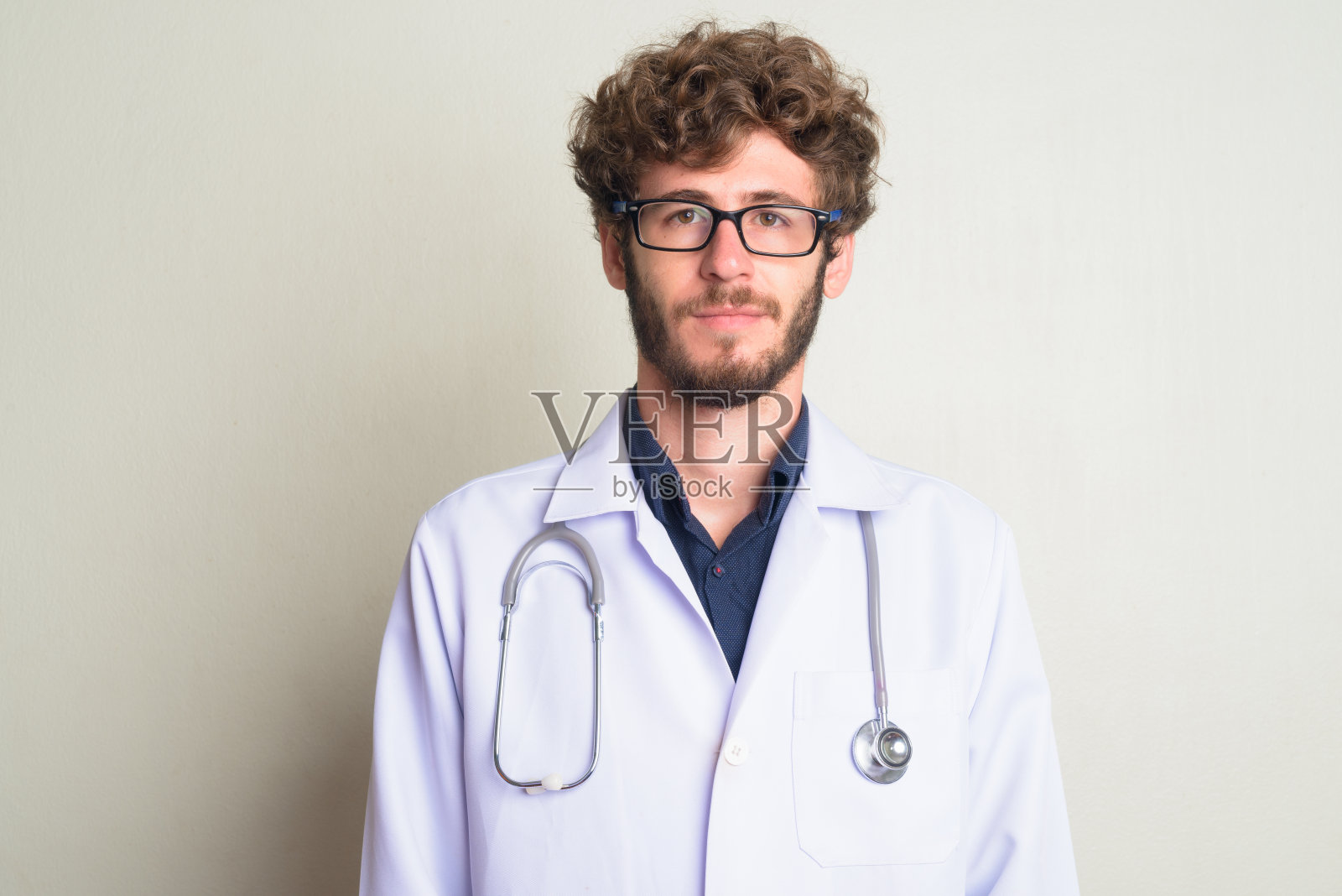 长着胡子的年轻医生,留着卷发,戴着眼镜照片摄影图片