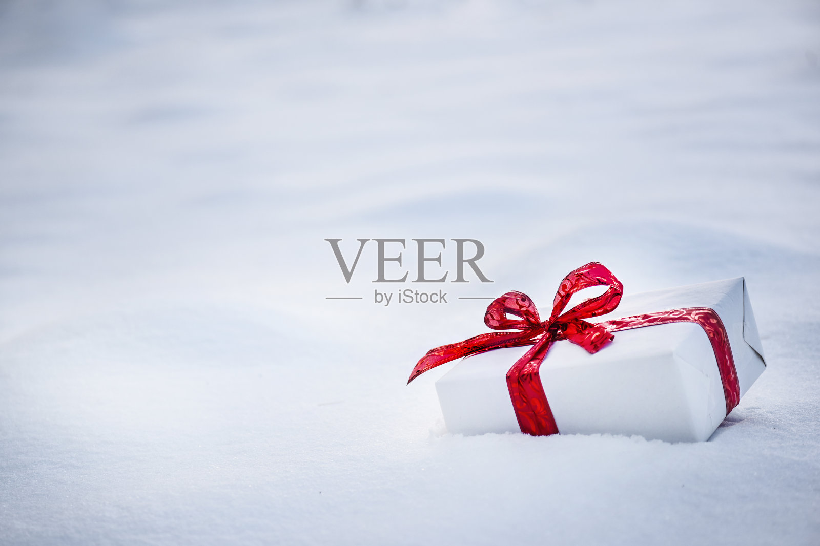 闪亮的圣诞礼物在雪与金色的灯和闪烁的背景照片摄影图片