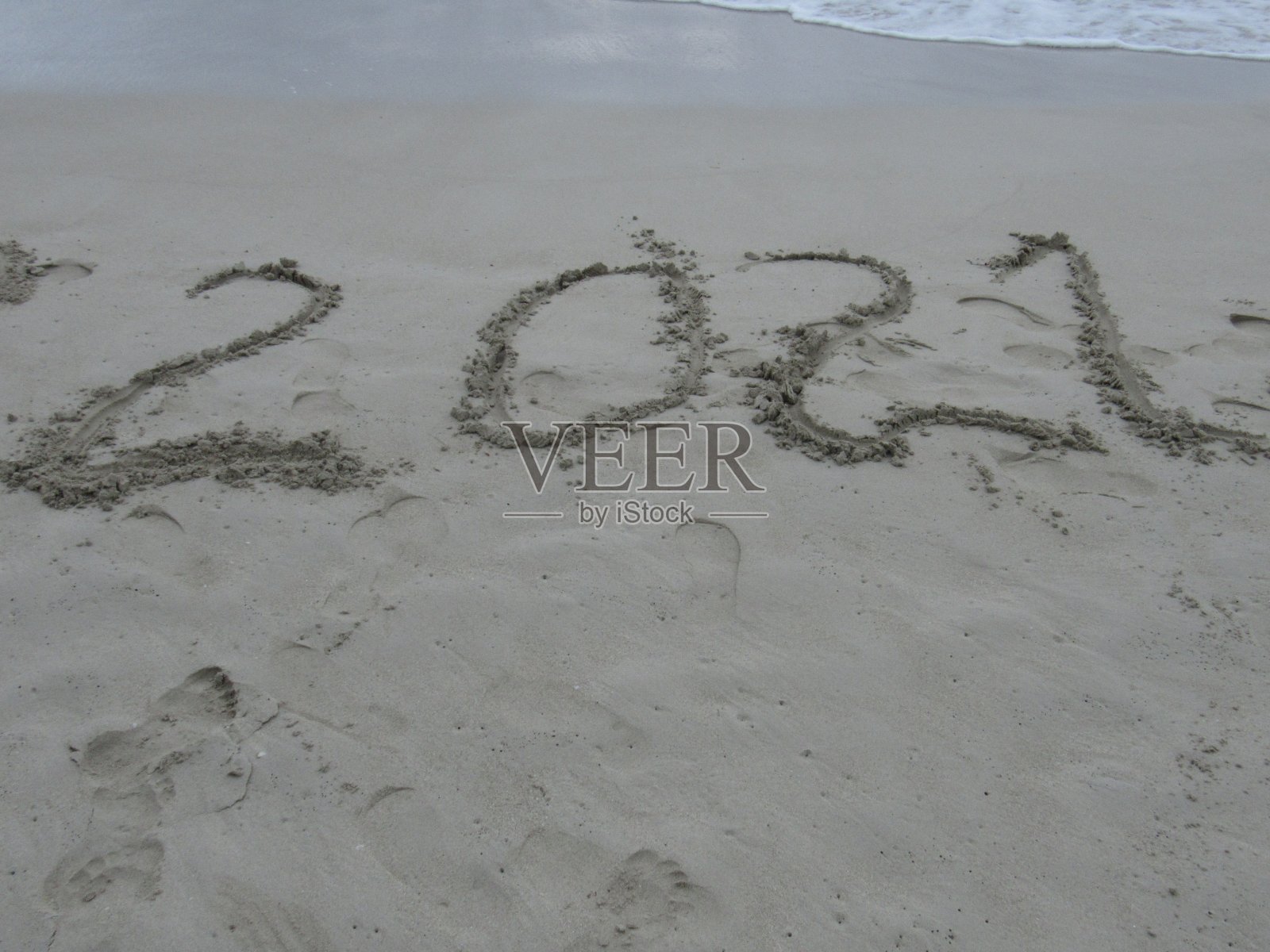 2021年新年快乐,海浪和湛蓝的大海在沙滩上刻下了字照片摄影图片