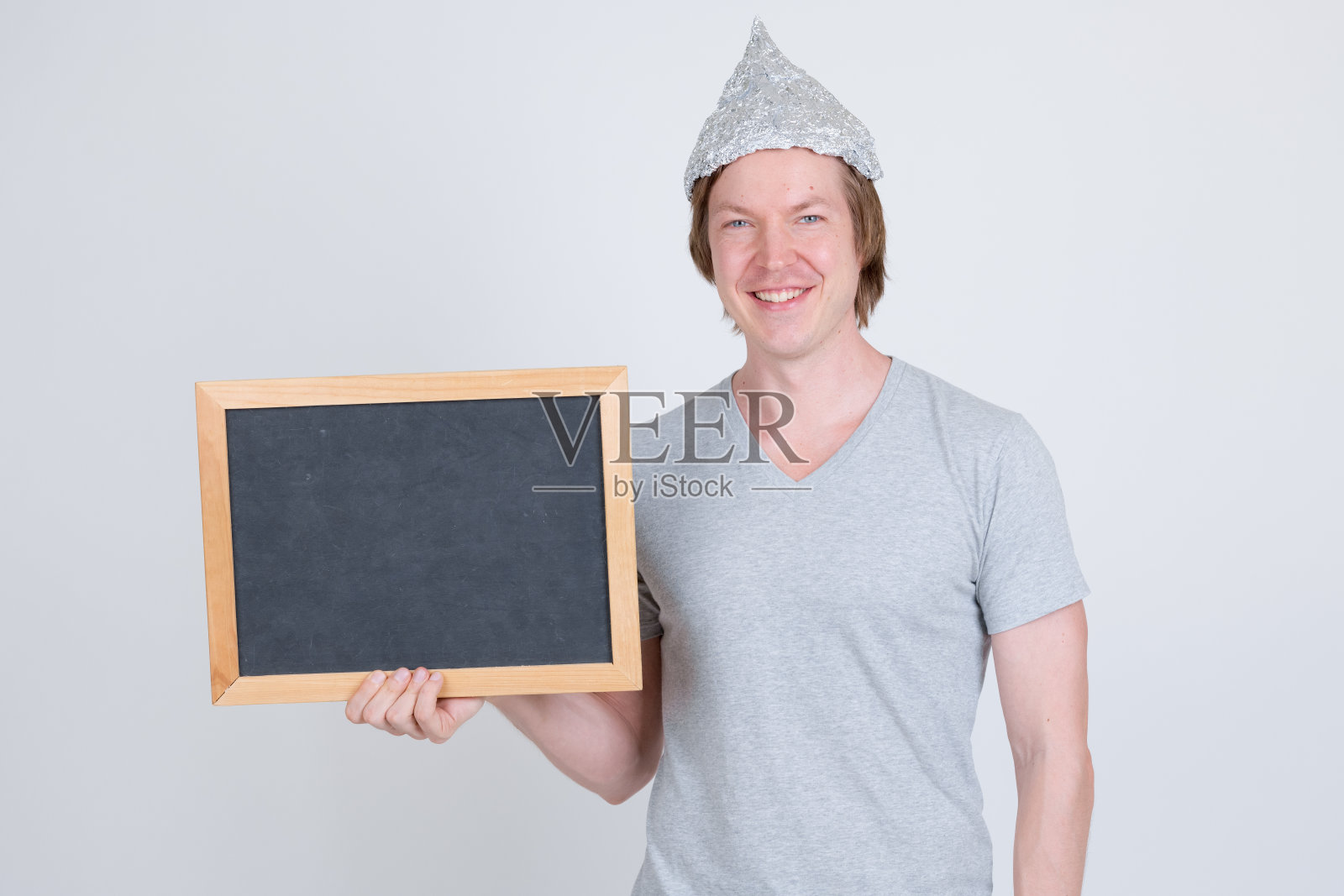 戴着锡箔帽,拿着黑板的快乐年轻男子照片摄影图片